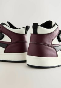 Hochschuh-Sneaker mit einem maronenfarbenen und schwarzen Leder-Obermaterial, einer weißen Zwischensohle und einer strukturierten schwarzen Gummisohle. Mit Akzenten in Form von Nähten.