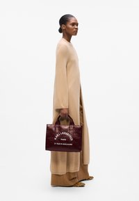 Burgundy glossy leather tote bag with top handles, featuring white text reading "KARL LAGERFELD PARIS 21 RUE ST-GUILLAUME."