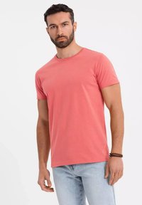 Tričko s krátkým rukávem a kulatým výstřihem v korálové barvě, vyrobené z bavlny, s hladkým povrchem a volným střihem, zkombinováno s světle modrými džíny.