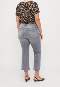 Leopardmönstrad topp med kort ärm som kombineras med högmidjade grå cropped jeans. Outfiten fulländas med svarta klackiga mule-skor.