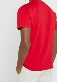 Rood katoenen T-shirt met korte mouwen, ronde hals en een effen structuur. De achterkant heeft een glad oppervlak zonder patronen of accenten.
