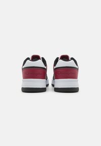 Zapatillas deportivas rojas y negras con una media suela blanca y una suela exterior negra. Presentan un logotipo grabado y un talón acolchado para mayor comodidad.