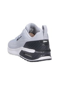 Grå atletisk sko med ovandel i mesh, mörk häl, fönster för luftdämpning och texturerad gummisula. Har en dragtab och märkesdetalj.