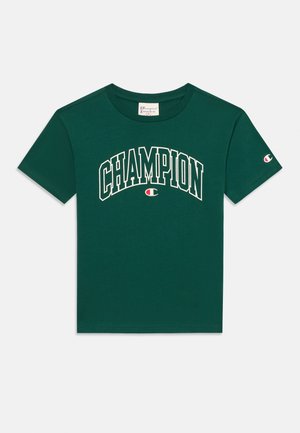 Vihreä puuvillapaita, jossa valkoinen "CHAMPION"-teksti kaartuu rinnan ylle, lyhyet hihat ja logo vasemmassa hihassa.