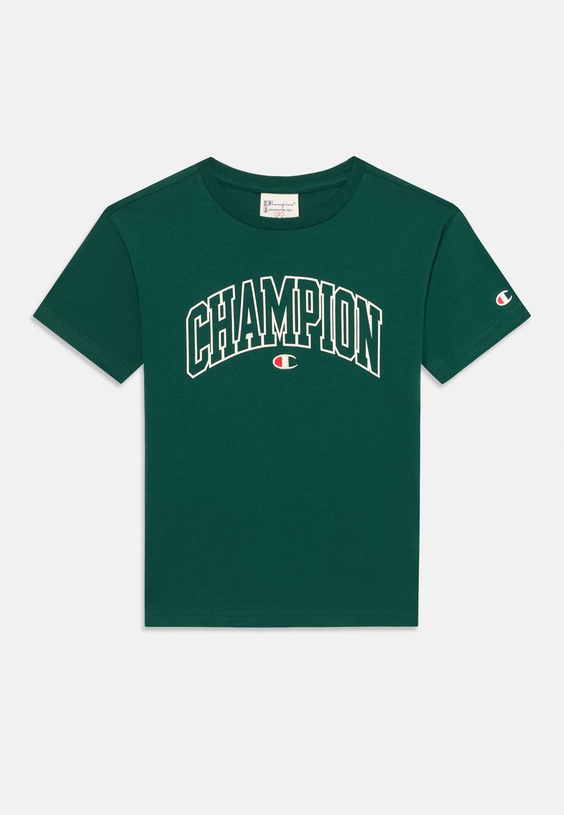 Πράσινο βαμβακερό μπλουζάκι με λευκό κείμενο "CHAMPION" που καμπυλώνει πάνω από το στήθος, κοντά μανίκια και λογότυπο στο αριστερό μανίκι.