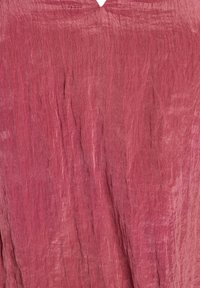 Naborani ružičasti materijal s vertikalnom teksturom i malim obrnutim V-izmjenom u središnjem dijelu na vrhu.