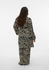 Ensemble deux pièces à motifs noir et beige avec manches longues et coupe ample, comprenant un haut fluide et un pantalon à jambes larges.