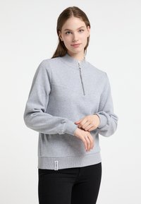 Grijze pullover sweatshirt van zacht materiaal met een opstaande kraag en een rits aan de voorkant. Voorzien van geribde manchetten en een subtiel label aan de zoom.