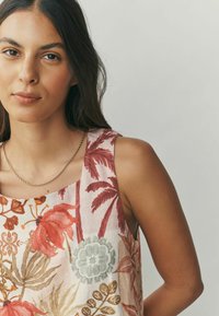 Õhulise kangaga lillesärk, mis on ilma varrukateta ja millel on punase ja rohelise taimemustriga pehme roosa taust ning lai kaelus.