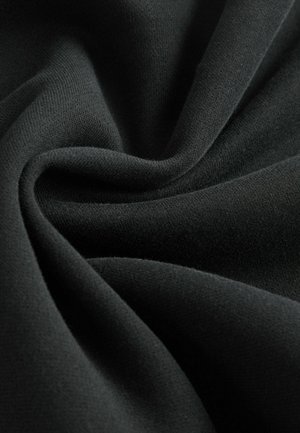 Musta kangas, jolla on sileä ja pehmeä rakenne, muistuttaen kevyttä neulosta. Materiaali laskeutuu poimuina ja näyttää hienovaraista kiiltoa.