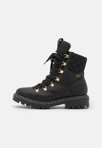 Bota de tobillo negra con cordones, cuero texturizado, tela acolchada en el cuello, detalles en dorado y suela de goma resistente con un profundo dibujo.