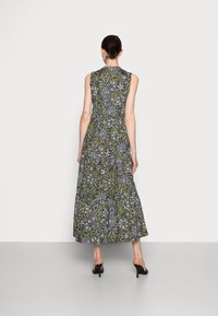 Vestido maxi de tela verde oliva con patrones de flores y hojas en negro. Diseño sin mangas con cintura entallada y falda fluida.