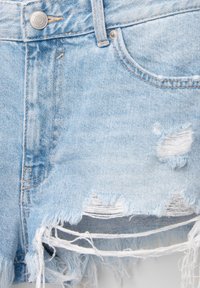 Shorts en denim bleu clair avec bords effilochés, des patchs usés et une fermeture à bouton en métal. Dispose d'un design à cinq poches.