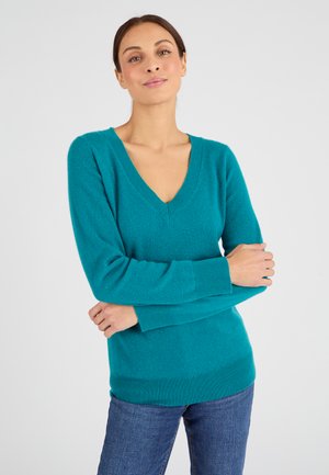 Teal V-hals trui met lange mouwen, gemaakt van zachte gebreide stof. Heeft ribgebreide manchetten en zoom voor een aangesloten look, gecombineerd met denim jeans.