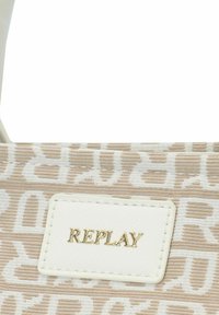 Beige gestreepte tas van textuurstof, met een wit etiket waarin "REPLAY" in gouden letters is gedrukt. Inclusief verstelbare schouderband.