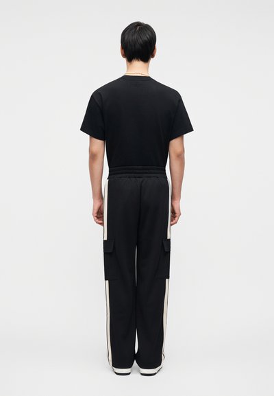 Μαύρο κοντομάνικο μπλουζάκι συνδυασμένο με μαύρο παντελόνι με κρέμ ρίγες και πλαϊνές τσέπες cargo. Απαλό ύφασμα και άνετη εφαρμογή.