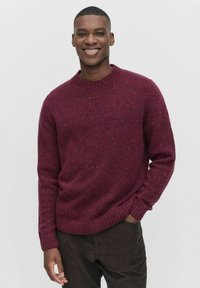 Bordeaux gebreide trui met een ronde halslijn en geribde manchetten. De stof heeft een gestructureerde textuur en subtiele kleurvariaties.
