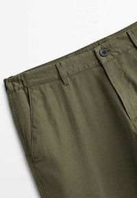 Oliwkowe spodnie z teksturowanej tkaniny, z zapięciem na guzik i przeszywaną talią z szlufkami na pasek.