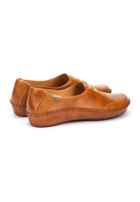 Zapatos de cuero marrón con un acabado suave y puntera redonda. Costuras decorativas a lo largo de los lados y una suela plana de goma que proporciona flexibilidad.