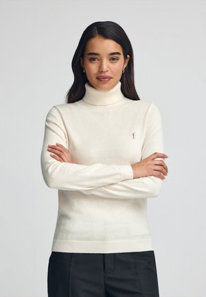 Maglione a colletto alto crema realizzato in morbido tessuto a maglia. Caratterizzato da maniche lunghe, polsini a coste e un piccolo logo sul petto. Design semplice e classico.