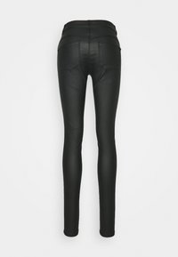 Jeans negros ajustados con una textura suave y elegante, de cintura alta y dos bolsillos traseros. El diseño es ceñido y aerodinámico.