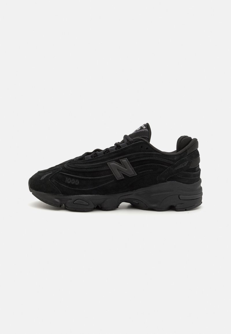 Black sneaker with suede and mesh upper, featuring textured detailing, padded collar, and rubber outsole. Prominent logo on the side.