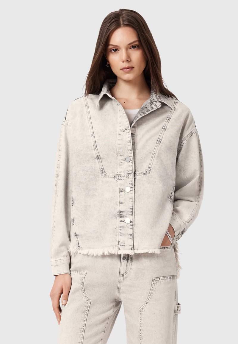 Jasnoszara kurtka dżinsowa o lekko skróconym kroju, z widocznym przeszyciem i postrzępionym dołem. Posiada duże kieszenie i srebrne zatrzaski.