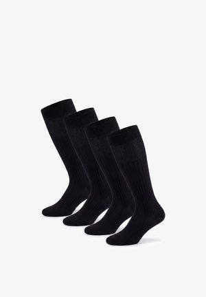 Vier Paar schwarze knielange gerippte Socken nebeneinander auf weißem Hintergrund angeordnet.