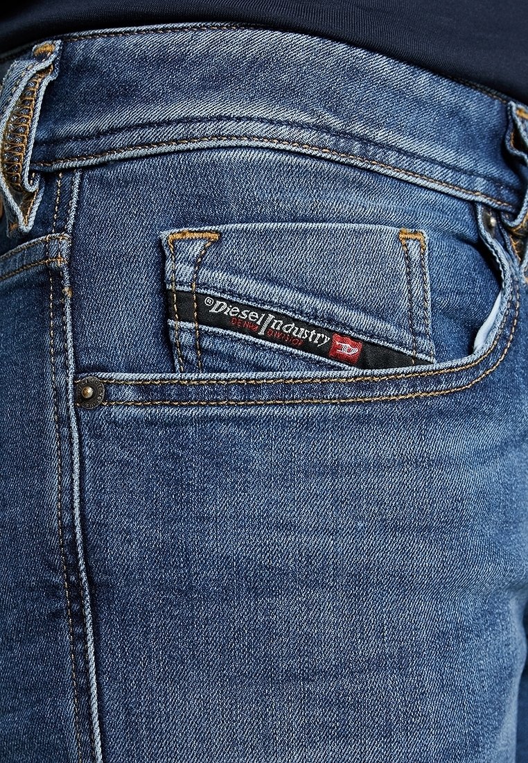 Jeans de mezclilla azul oscuro con un bolsillo trasero que lleva una etiqueta negra y roja de "Diesel Industry", acentuada con costuras doradas y un detalle de remache.