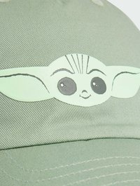 Light green cap with textured fabric featuring a printed cartoon character face with large eyes and pointy ears.