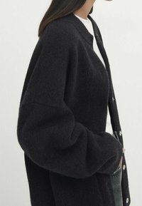 Donkere wollen cardigan met een ontspannen pasvorm, voorzien van een ronde halslijn, knoopsluiting en brede mouwen. Textiele stof met een subtiele dikte.