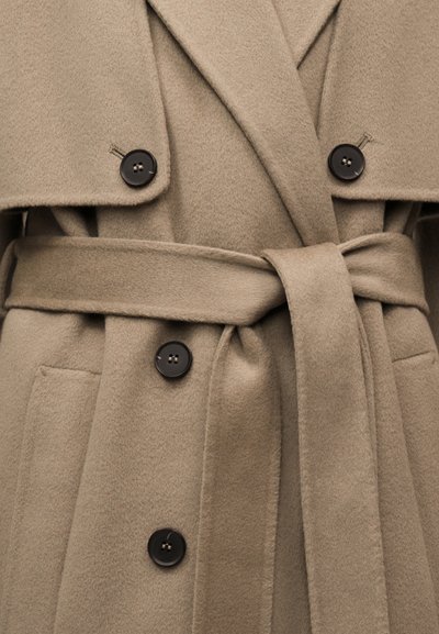 Παλτό από γκριζοκαφέ μαλλί με μαύρα κουμπιά, φαρδιές πέτσες, μπροστινές τσέπες και ζώνη στο ίδιο χρώμα δεμένη στη μέση.