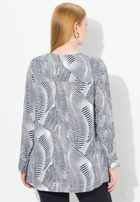 Camicia a maniche lunghe con motivo foglia navy e bianco. Vestibilità ampia, orlo arrotondato, con polsini buttoned e scollo a barchetta.