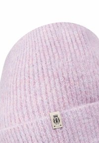 Light purple knitted beanie with ribbed texture. Features a small fabric tag with a graphic logo. Soft and cozy appearance.