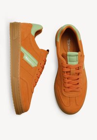 Paire de baskets en suède orange avec des accents verts, semelles en caoutchouc plates et lacets, vues de côté et de dessus.