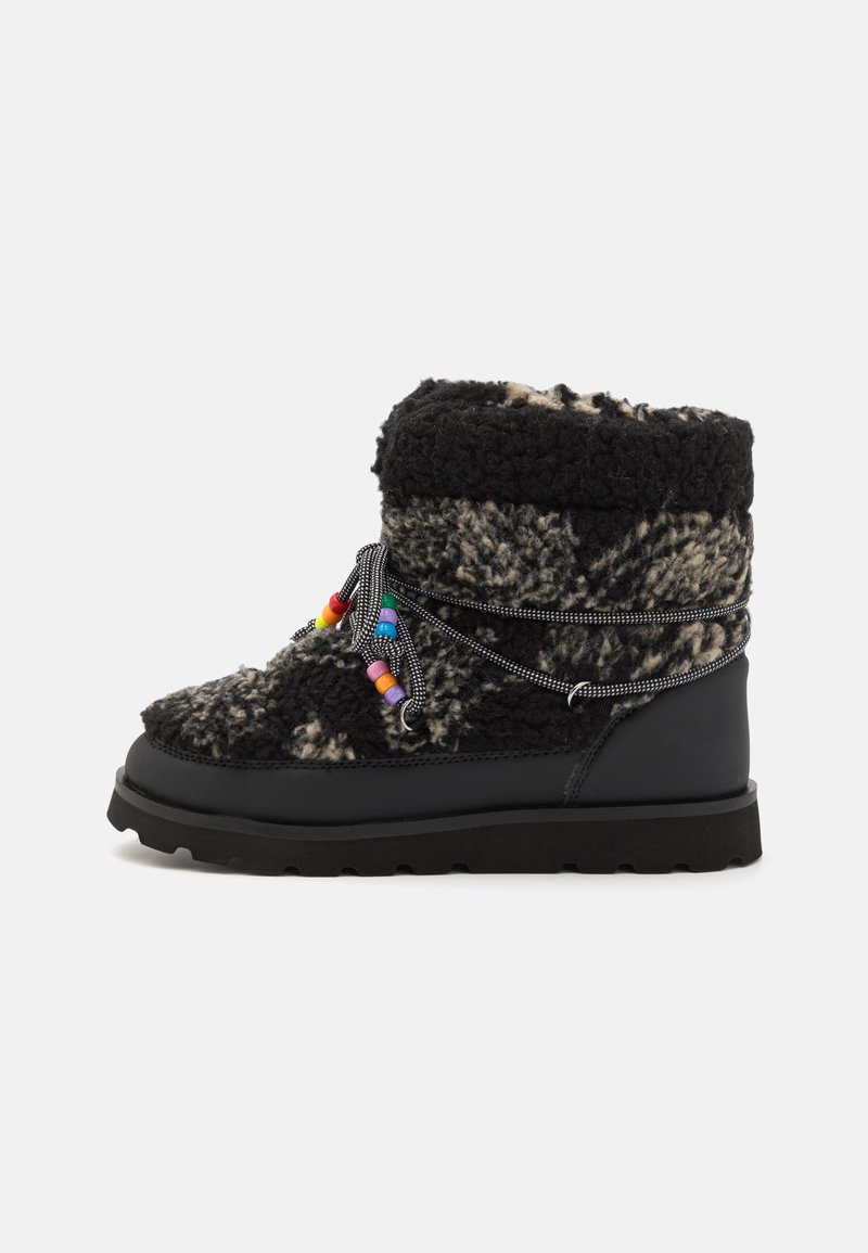 Svart-hvitt mønstrete ullstøvel med en myk, lodden tekstur, gummi såle og fargerike perler på snøringene for justering.