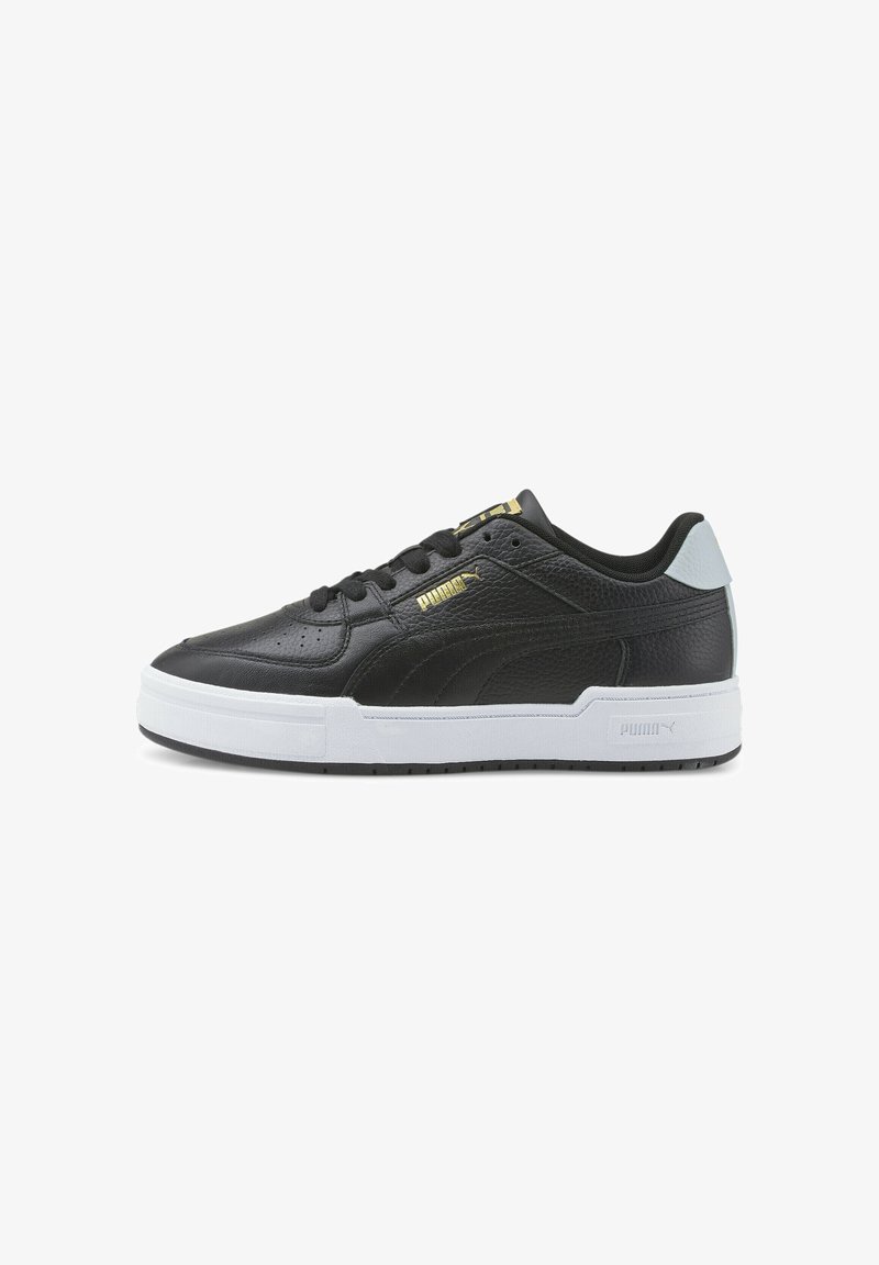 Baskets basses noires Puma avec semelle blanche, logo Puma doré sur le côté et languette blanche au talon, vues de profil.