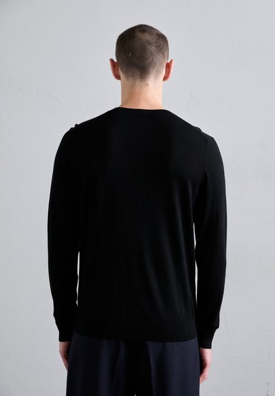 Svart strikket genser med lange ermer, rund hals og ribbestrikket kant. Materialet ser glatt ut med et enkelt, minimalistisk design.