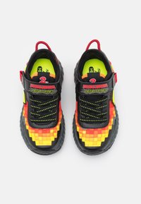 Svarta och gula sneakers med pixelerat röd-orange mönster, texturerad gummisula, bred tunga, elastiska snören och förstärkt häl.