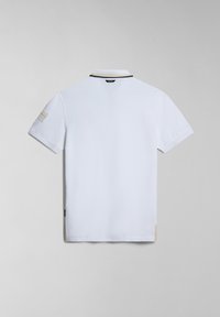 Polo bianco con colletto a righe nere e dorate, maniche corte e una toppa texturizzata sulla manica sinistra.