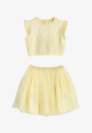 Geltonas megztas berankovis palaidinė su baltomis gėlių aplikacijomis ir derančiais geltonais tiulio sijonu su gėlių siuvinėjimu.