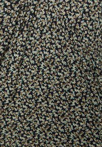 Tissu noir avec un petit motif floral en bleu clair, jaune et vert. Présente des plis pour ajouter de la texture et du mouvement.