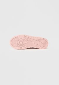 Σόλα ενός ροζ αθλητικού παπουτσιού με υφή πέλματος, κυκλικά και γραμμικά σχέδια, και το ανάγλυφο λογότυπο της Coach στο κέντρο.