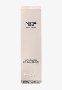 Masque purifiant dans une boîte rectangulaire rose pâle. Le texte noir inclut le nom du produit et des détails. Des accents dorés et le volume sont notés en bas.