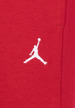 Weiße Silhouette eines Basketballspielers, der mit einem ausgestreckten Arm springt und einen Ball hält, auf rotem Stoff gestickt.