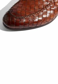Scarpa in pelle intrecciata marrone con punta rotonda, caratterizzata da una texture liscia e cuciture decorative lungo il bordo.
