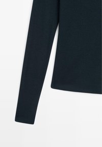 Langärmliges Oberteil aus dunkelblauem Stoff. Mit weicher Textur, figurbetontem Design und geradem Schnitt am Saum. Minimale Nähte und saubere Kanten.