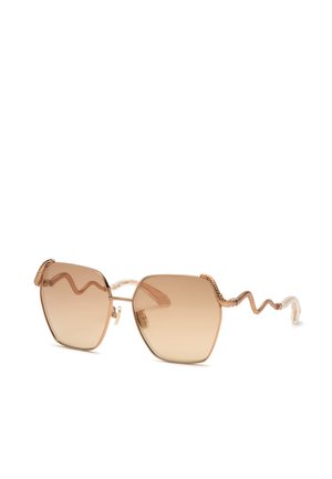 Lunettes de soleil avec de grandes verres hexagonaux dégradés marron et montures en fil d’or avec des branches en forme de serpent.