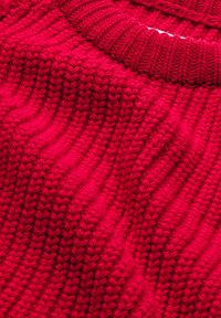 Roter gestrickter Pullover mit geripptem Rundhalsausschnitt und strukturiertem Wellenmuster. Das Material wirkt weich mit einer dichten Webart.