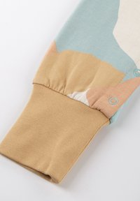 Long-sleeve top featuring a color-block design in light blue, beige, and peach. Cuffed sleeves with button detail in a soft, textured fabric.